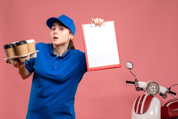 Mensajero femenino de vista frontal con café de entrega y nota de archivo en el trabajador de servicio uniforme de bicicleta de trabajo de entrega de trabajo rosa