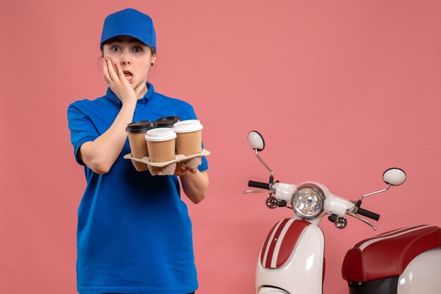 Mensajero femenino de vista frontal con café de entrega en el trabajo de servicio de entrega de trabajo rosa trabajador en bicicleta