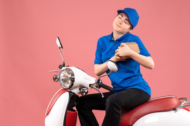 Mensajero femenino de vista frontal con pequeño paquete de comida en la bicicleta de entrega de alimentos de trabajador uniforme de color rosa trabajo