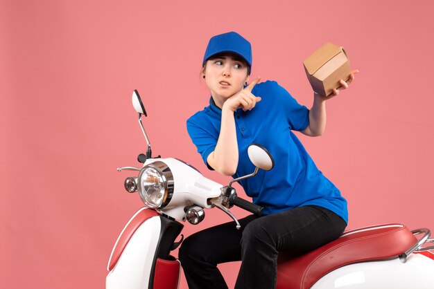 Mensajero femenino de vista frontal con pequeño paquete de comida en color rosa trabajo uniforme trabajador entrega de alimentos