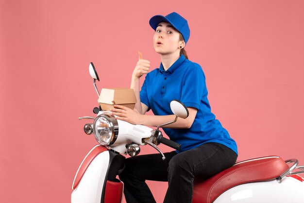 Mensajero femenino de vista frontal con un pequeño paquete de comida en un trabajo de color rosa trabajador entrega de alimentos servicio uniforme de bicicleta