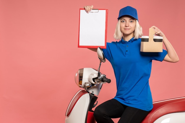 Foto gratuita mensajero femenino de la vista frontal con tazas de café en el trabajo uniforme del trabajador del color del trabajo del servicio de entrega rosado
