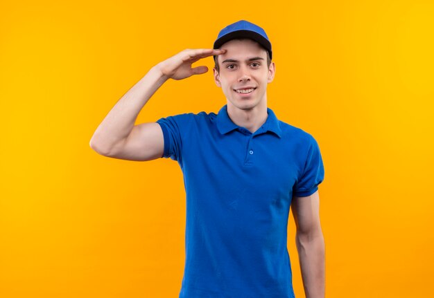 Mensajero joven con uniforme azul y gorra azul haciendo feliz honor