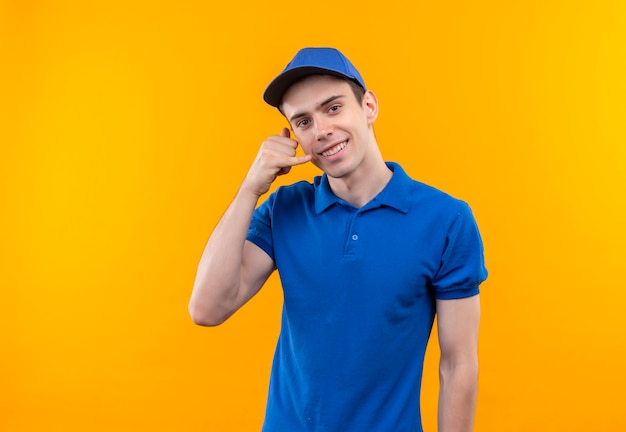 Mensajero joven con uniforme azul y gorra azul haciendo feliz llamame con la mano