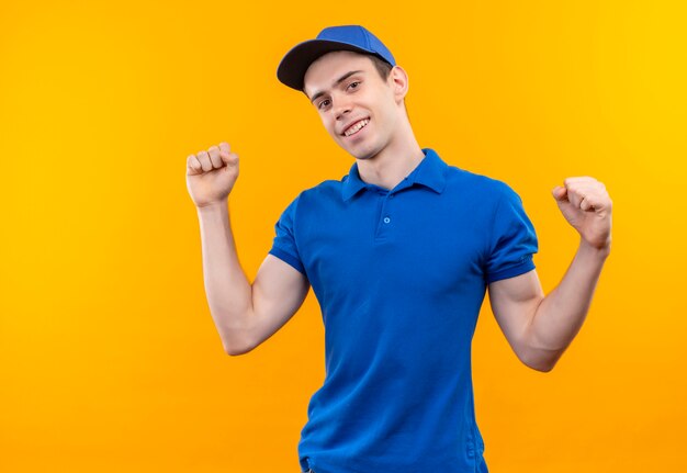 Mensajero joven con uniforme azul y gorra azul haciendo puño feliz