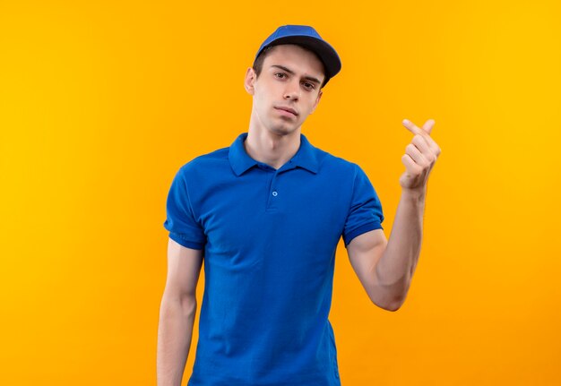 Mensajero joven vistiendo uniforme azul y gorra azul mostrando dinero con los dedos