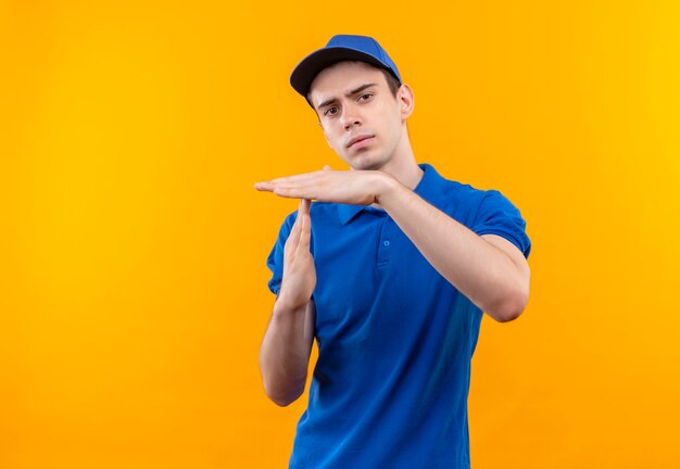 Mensajero joven vistiendo uniforme azul y gorra azul muestra romper con las manos