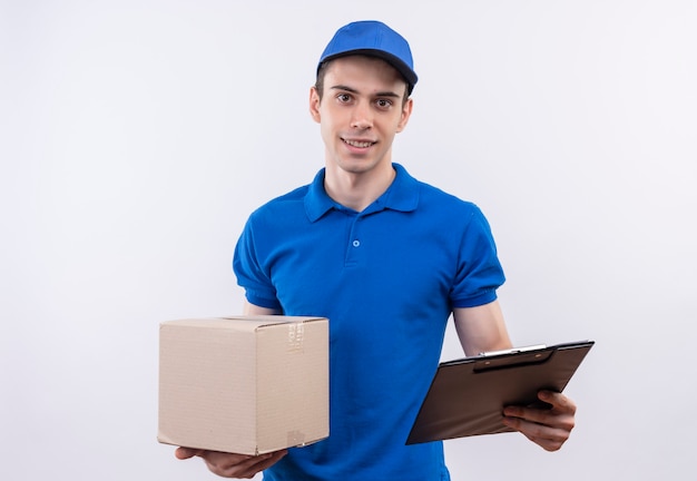 Mensajero joven vistiendo uniforme azul y gorra azul sosteniendo una caja y un portapapeles