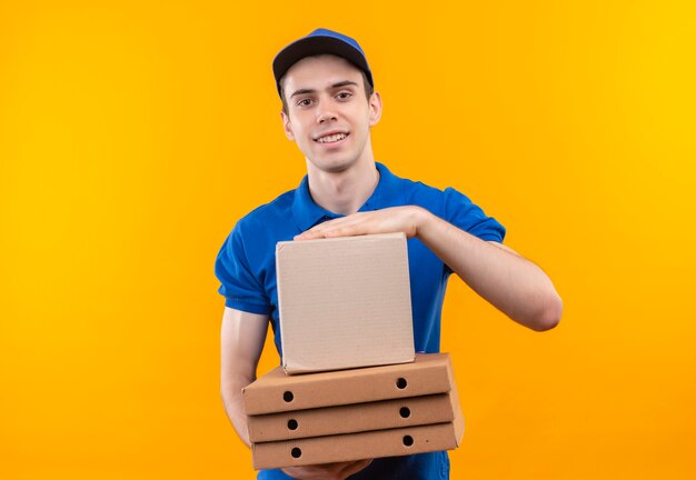 Mensajero joven vistiendo uniforme azul y gorra azul tiene cajas