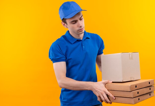 Mensajero joven vistiendo uniforme azul y gorra azul tiene cajas