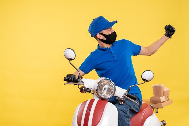 Mensajero masculino joven de la vista frontal en uniforme azul sobre fondo amarillo