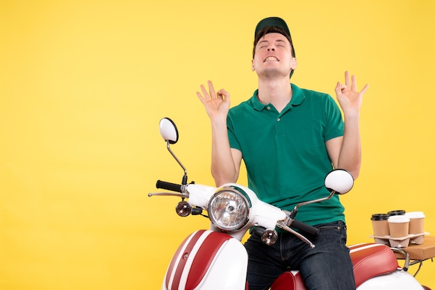 Mensajero masculino joven de la vista frontal en uniforme verde en amarillo de la bici