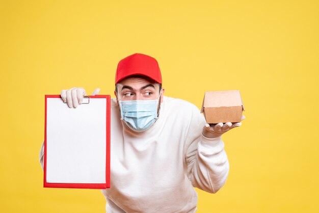 Mensajero masculino en máscara con nota de archivo y pequeño paquete de comida en amarillo