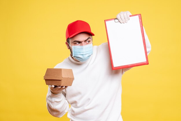 Mensajero masculino en máscara con nota de archivo y pequeño paquete de comida en amarillo