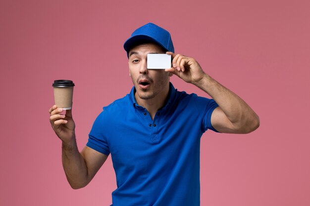 Mensajero masculino en uniforme azul con café y tarjeta de plástico en rosa, entrega de trabajo de servicio uniforme