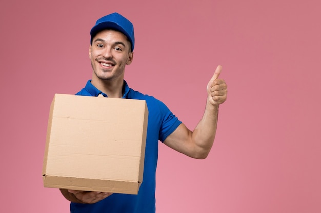 Mensajero masculino en uniforme azul con caja de comida en rosa, servicio de entrega uniforme de trabajador de trabajo