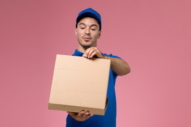 Mensajero masculino en uniforme azul con caja de entrega de comida y apertura en rosa, servicio de entrega uniforme del trabajador