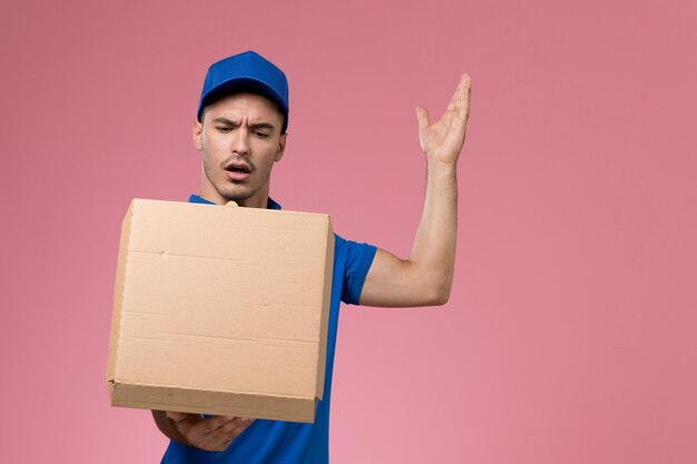 Mensajero masculino en uniforme azul con caja de entrega de comida en rosa, servicio de entrega uniforme