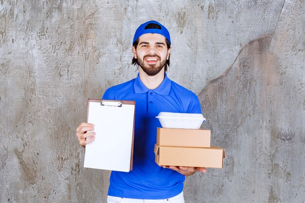 Mensajero masculino en uniforme azul que lleva cajas de cartón y plástico y presenta la lista de firmas