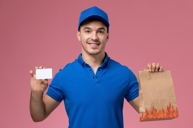 Mensajero masculino en uniforme azul con tarjeta y paquete de alimentos en rosa, entrega de trabajo de servicio uniforme