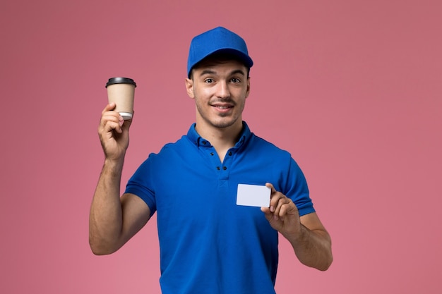 Mensajero masculino en uniforme azul con taza de café y tarjeta en rosa, entrega de trabajo de servicio uniforme