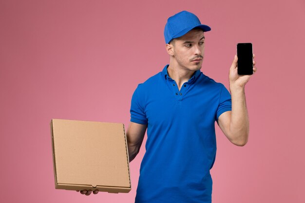 Mensajero masculino en uniforme azul con teléfono de caja de comida de entrega en rosa, servicio de trabajador de trabajo uniforme entrega