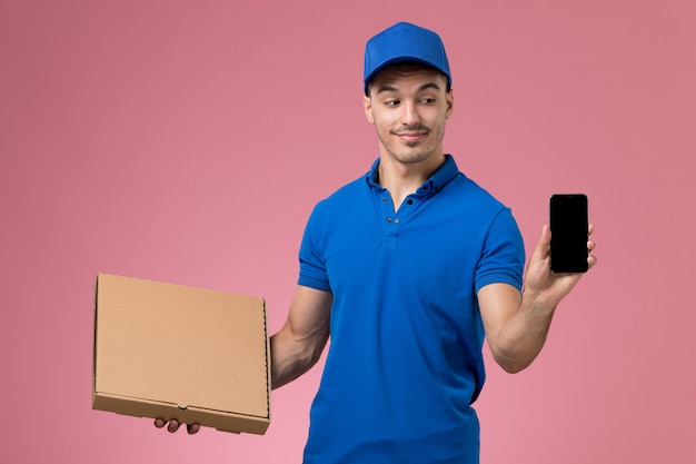 Mensajero masculino en uniforme azul con teléfono de caja de comida de entrega en rosa, servicio de trabajador de trabajo uniforme entrega