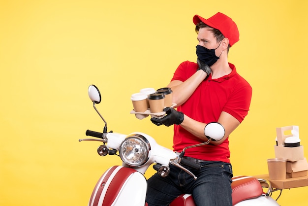 Mensajero masculino de vista frontal en bicicleta en máscara con café en amarillo
