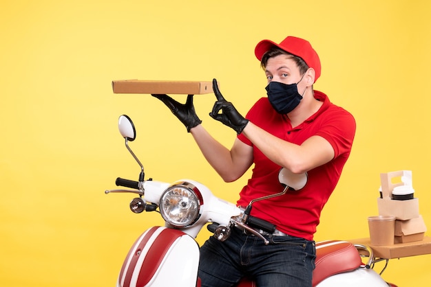 Mensajero masculino de vista frontal en bicicleta en máscara con caja de comida en amarillo