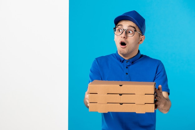 Mensajero masculino de vista frontal con cajas de pizza de entrega en azul