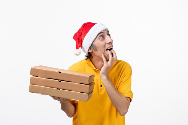 Mensajero masculino de vista frontal con cajas de pizza en servicio uniforme de trabajo de pared blanca