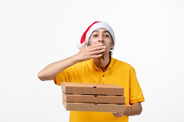 Mensajero masculino de vista frontal con cajas de pizza en uniforme de entrega de servicio de trabajo de pared blanca