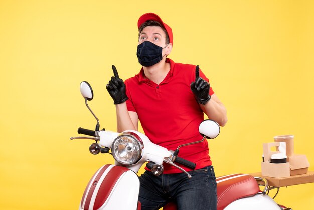 Mensajero masculino de vista frontal en guantes uniformes y máscara en amarillo