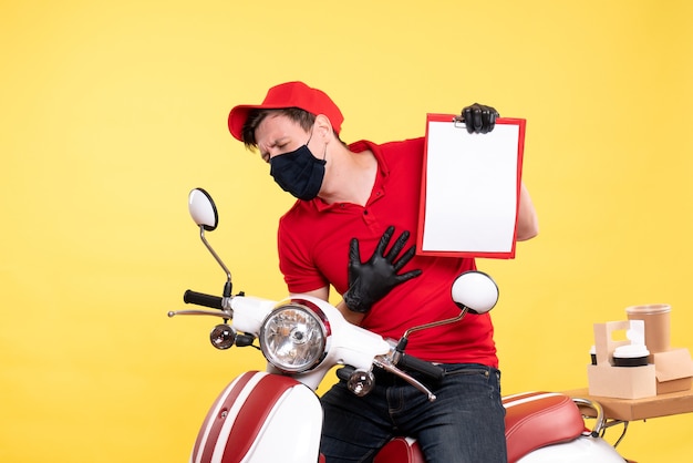 Foto gratuita mensajero masculino de la vista frontal en la máscara que sostiene la nota del archivo en amarillo