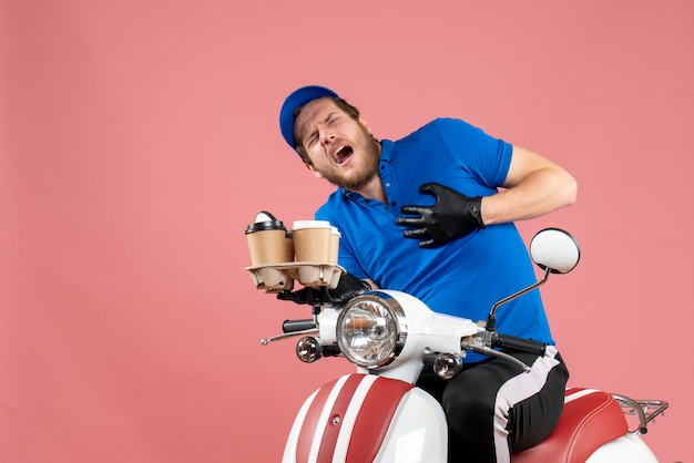 Mensajero masculino de vista frontal sentado en bicicleta y sosteniendo tazas de café en el rosa