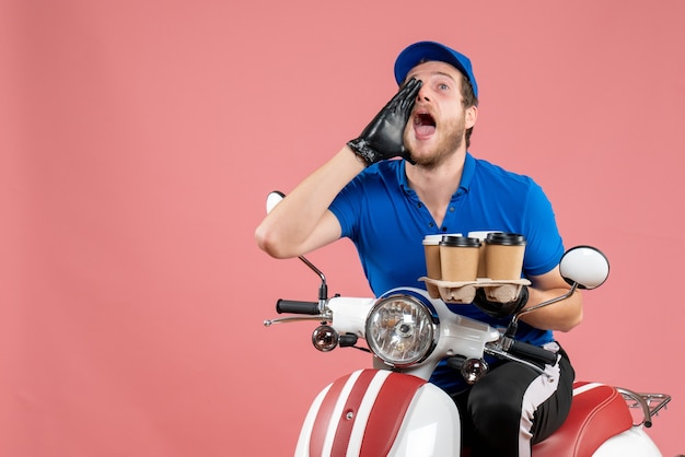 Mensajero masculino de vista frontal sentado en bicicleta y sosteniendo tazas de café en el rosa