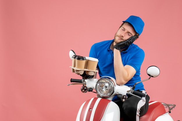 Mensajero masculino de vista frontal sentado en bicicleta y sosteniendo tazas de café en el rosa
