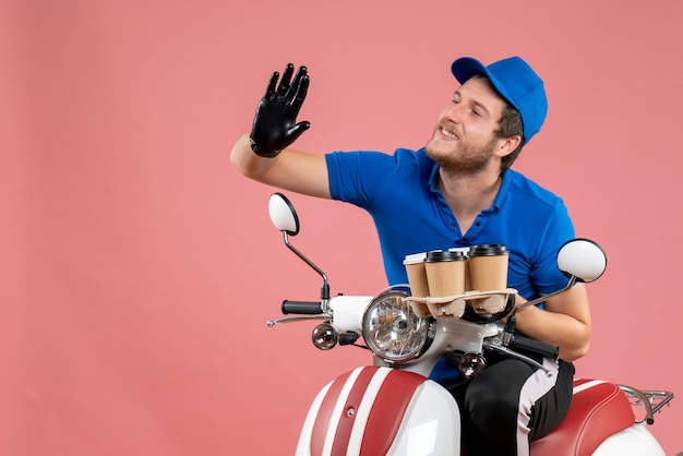 Mensajero masculino de vista frontal sentado en bicicleta y sosteniendo tazas de café en el rosa