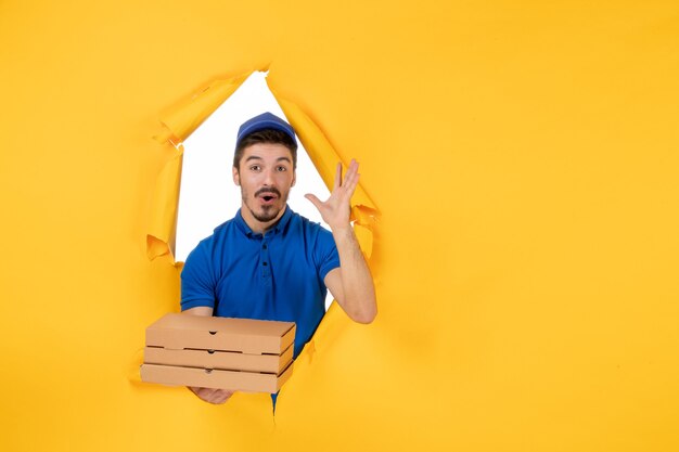 Mensajero masculino de vista frontal sosteniendo cajas de pizza en el espacio amarillo