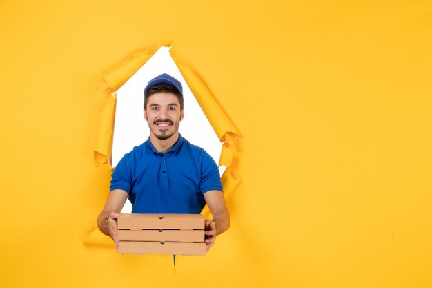 Mensajero masculino de vista frontal sosteniendo cajas de pizza en el espacio amarillo