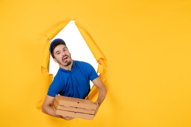 Mensajero masculino de vista frontal sosteniendo cajas de pizza en el espacio amarillo