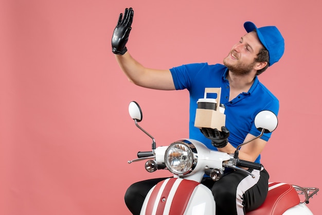 Foto gratuita mensajero masculino de vista frontal en uniforme azul con café en la bicicleta de trabajo de trabajador de servicio de comida rápida de trabajo de color rosa