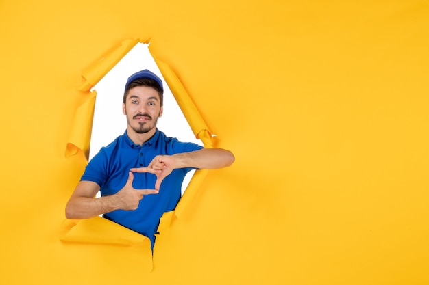 Foto gratuita mensajero masculino de vista frontal en uniforme azul en el espacio amarillo