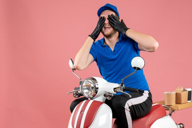 Mensajero masculino de vista frontal en uniforme azul y guantes en el trabajo de color rosa, servicio de comida rápida, trabajo de comida, bicicleta de entrega