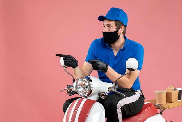 Mensajero masculino de vista frontal en uniforme azul y máscara en la entrega de trabajo rosa servicio de comida rápida trabajo en bicicleta covid- virus de la comida