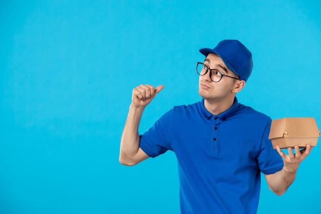 Mensajero masculino de vista frontal en uniforme azul con pequeño paquete de comida azul