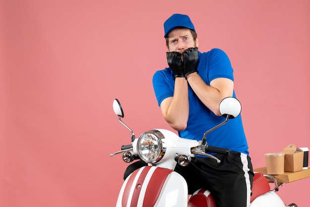 Mensajero masculino de vista frontal en uniforme azul en un servicio de trabajo de comida rápida de trabajo rosa entrega de bicicletas de color