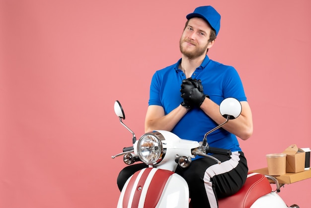 Foto gratuita mensajero masculino de vista frontal en uniforme azul en servicio de trabajo de trabajo de entrega de bicicletas de alimentos rosa servicio de comida rápida