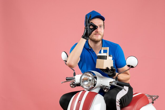 Mensajero masculino de vista frontal en uniforme azul sosteniendo café en la bicicleta de trabajo de trabajador de servicio de entrega de comida rápida de trabajo de color rosa