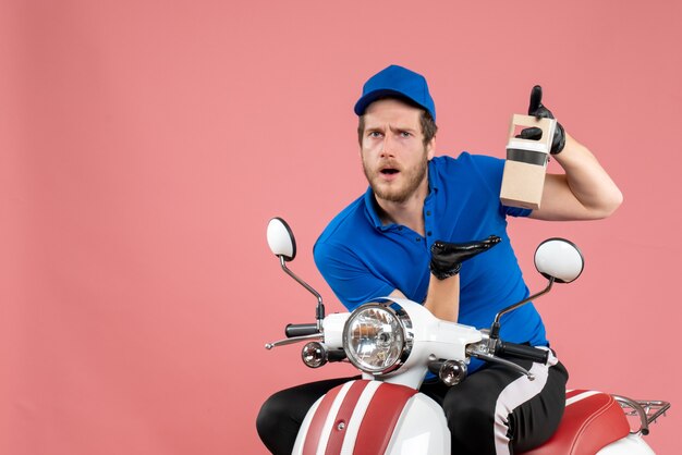 Mensajero masculino de vista frontal en uniforme azul sosteniendo café en colores rosados trabajo servicio de comida rápida entrega de trabajador bicicleta de trabajo